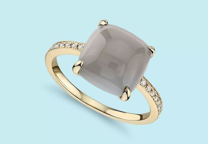 A gray cabochon moonstone gemstone set in a yellow gold ring